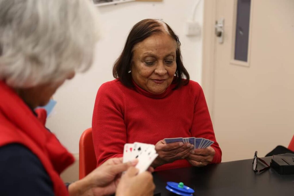 Two women holding cards, playing bridge