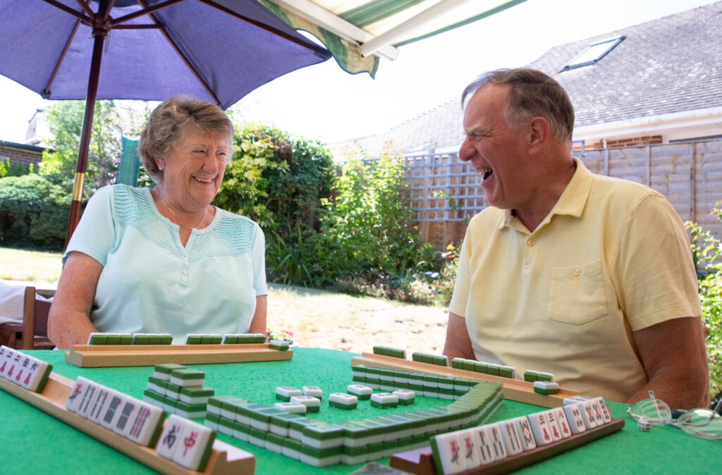 A man and a woman laugh together while playing Mahjong