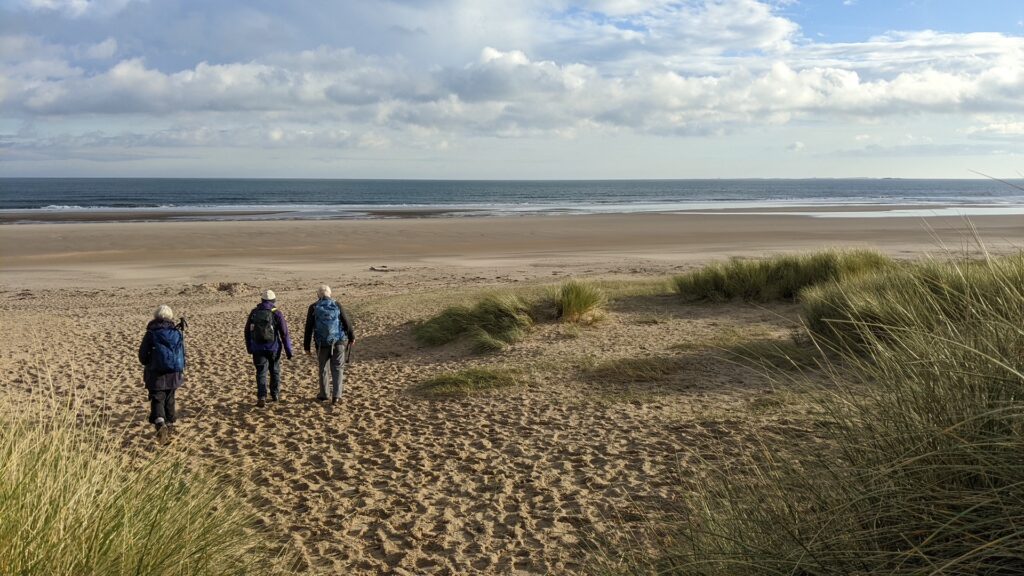 Three people walking on the beach at Ross Back Sands