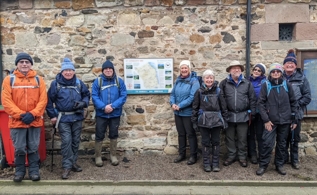 Nine people standing by a map on the wall, at the end of St Cuthbert's Way